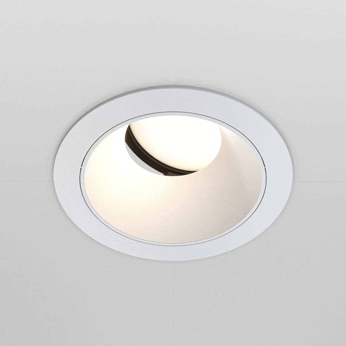 The Share Round Recessed Swivel Downlight in white offers a minimalist lighting design with a circular trim, partially illuminating interior spaces.