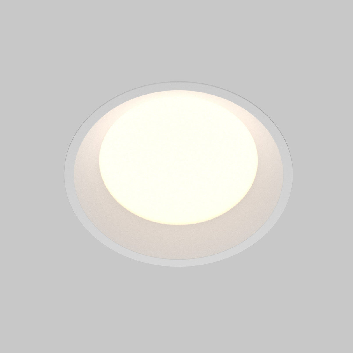 The Okno CCT LED Round Recessed Downlight 18W 3000-6000K in white emits soft, diffused light against a gray backdrop. Its simple, modern design features adjustable color temperature for custom ambiance.