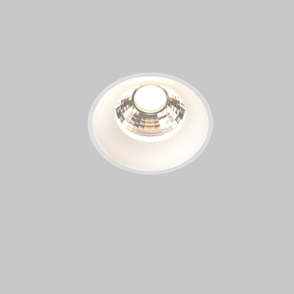 The Round LED Recessed Trimless Downlight 12W 3000K - White boasts a circular design with a metallic finish, emitting a bright, warm glow. Its minimalist aesthetic is enhanced by a reflective interior and complements any plain, light gray background.