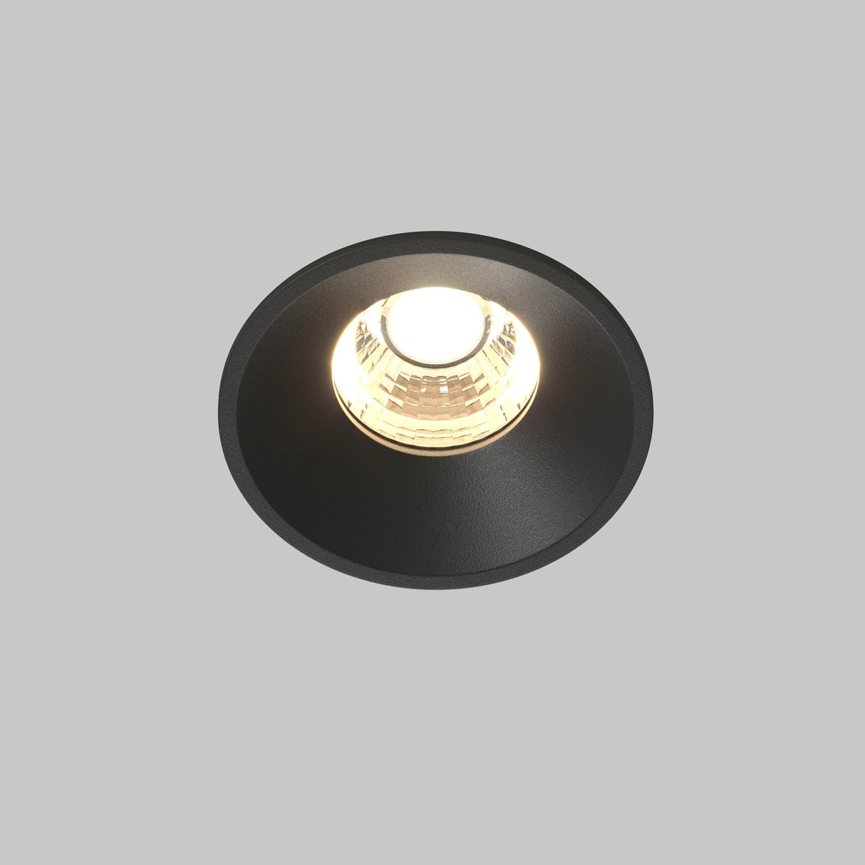 The Round LED Recessed Downlight 7W 3000K - Black emits a soft, warm glow, seamlessly enhancing modern interiors lighting against a plain gray backdrop.