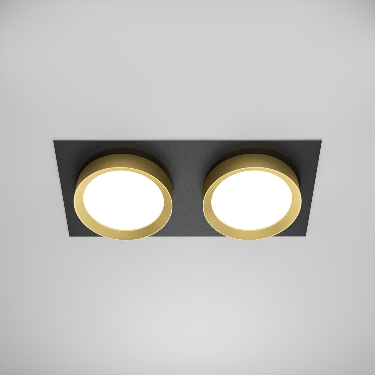 The Hoop Twin Fixed Rectangular Recessed Downlight in black and gold elegantly accents a white ceiling with its dual round lights on a sleek base, embodying the timeless allure of these two classic colors.