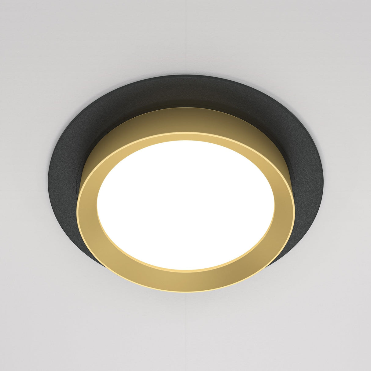 The Hoop Single Fixed Round Recessed Downlight in black and gold features an energy-efficient LED center and a golden border, mounted on a white ceiling for a striking contrast with its sleek design.