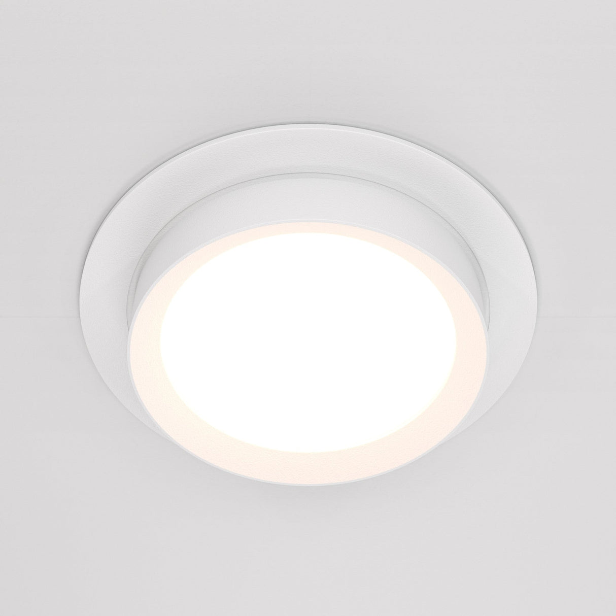 The Hoop Single Fixed Round Recessed Downlight - White is a sleek, circular fixture with a glowing center that stands out against a white background, providing an energy-efficient lighting solution.