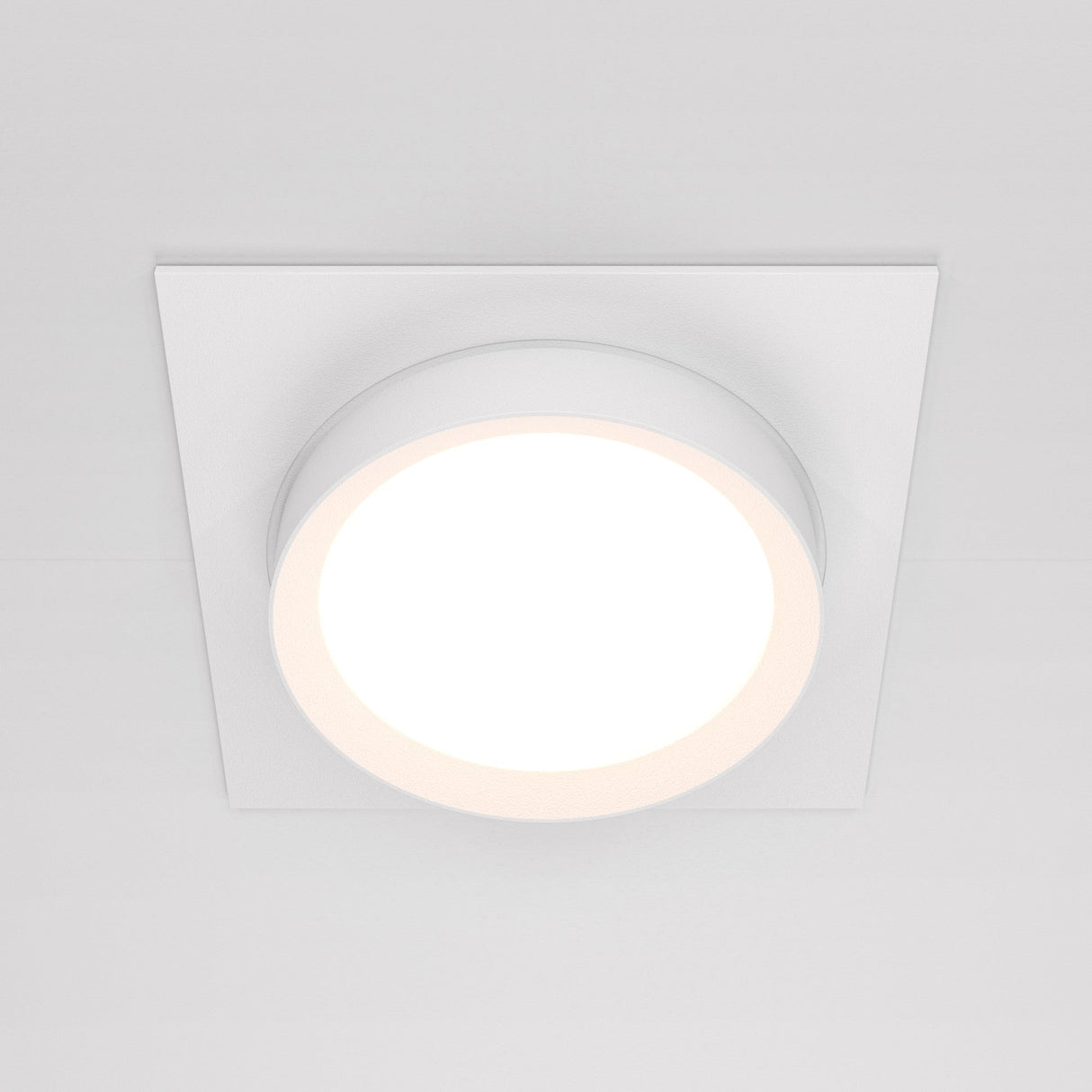 The Hoop Single Fixed Square Recessed Downlight in white is a modern circular LED ceiling light with a white square frame. It emits a bright, even glow, enhancing modern interiors and seamlessly blending with a plain white ceiling for a minimalist aesthetic.
