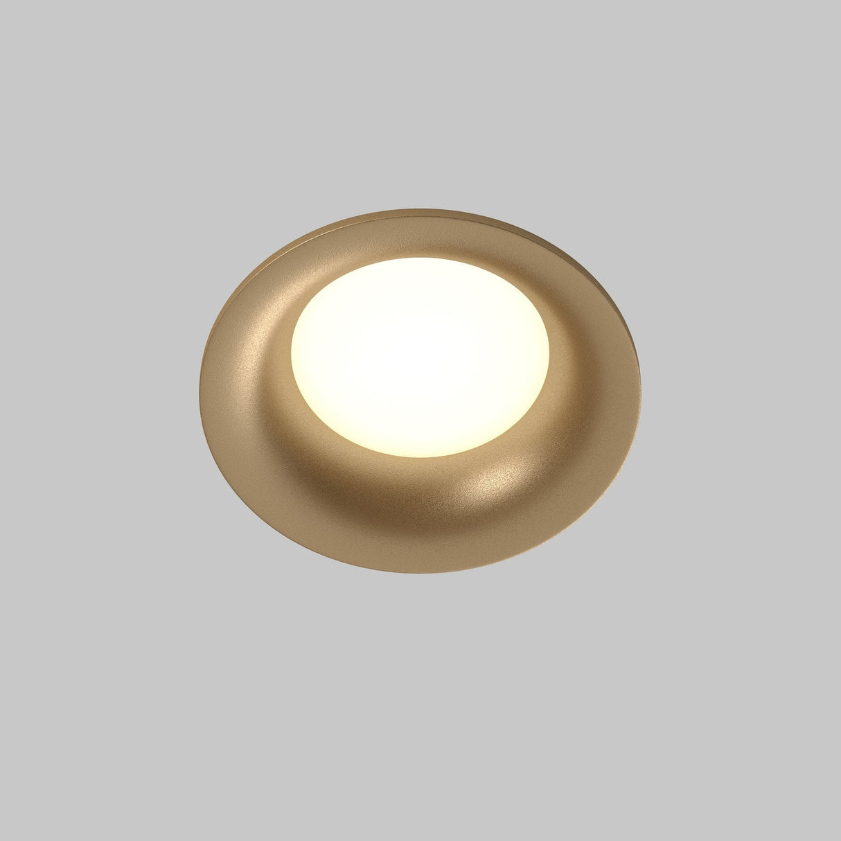 Close-up of the Slim Outdoor Fixed Round Recessed Downlight - Matte Gold, casting a warm glow against a smooth gray background.