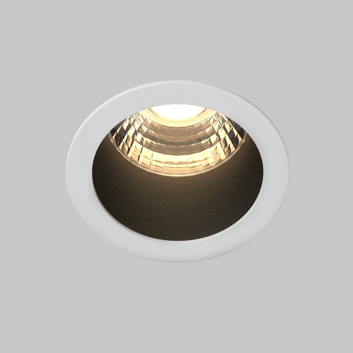 Close-up view of the Minor LED Recessed Downlight 9W 3000K with a circular frame and illuminated bulb. Its modern design features a reflective inner surface for enhanced brightness and energy efficiency, set against a plain gray backdrop.