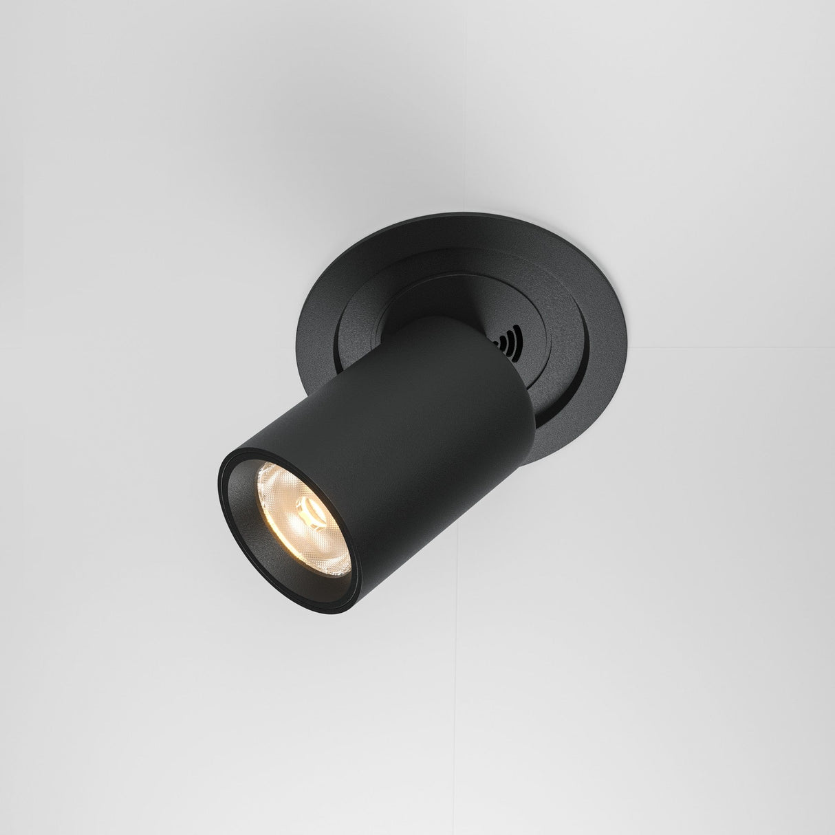The Hidden Adjustable Retractable In-Out LED Recessed Downlight in black offers a sleek, minimalist design. This cylindrical ceiling spotlight mounts on a white ceiling, features energy-efficient LED technology, and emits a warm glow suitable for any space.
