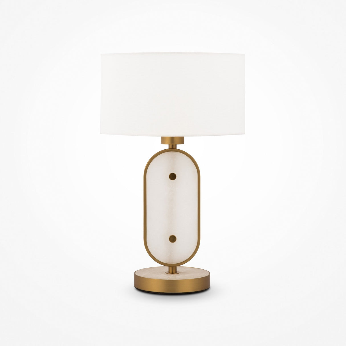 The Marmo Table Lamp in gold features a white cylindrical lampshade, a stylish base with a gold frame surrounding an oval natural stone panel, and rests on a circular gold platform.