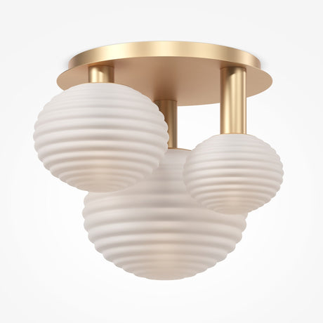 The Reels 3 Light Semi-Flush - Gold features three ribbed, frosted glass globes in varied sizes on a circular gold-finish base. The globes elegantly hang in a triangular arrangement for luxurious lighting.