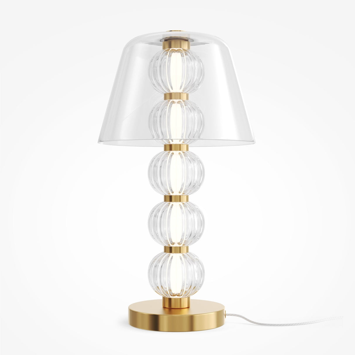 The Amulet LED Table Lamp features a gold brass base with five ribbed clear glass spheres, a wide transparent conical shade, and a white power cord.