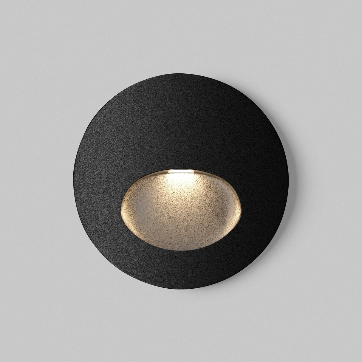 The Bil Outdoor LED Recessed Wall Light in sleek black features a circular design on a gray background, offering a subtle glow at its center. Its IP54 rating ensures elegance and durability for outdoor use.