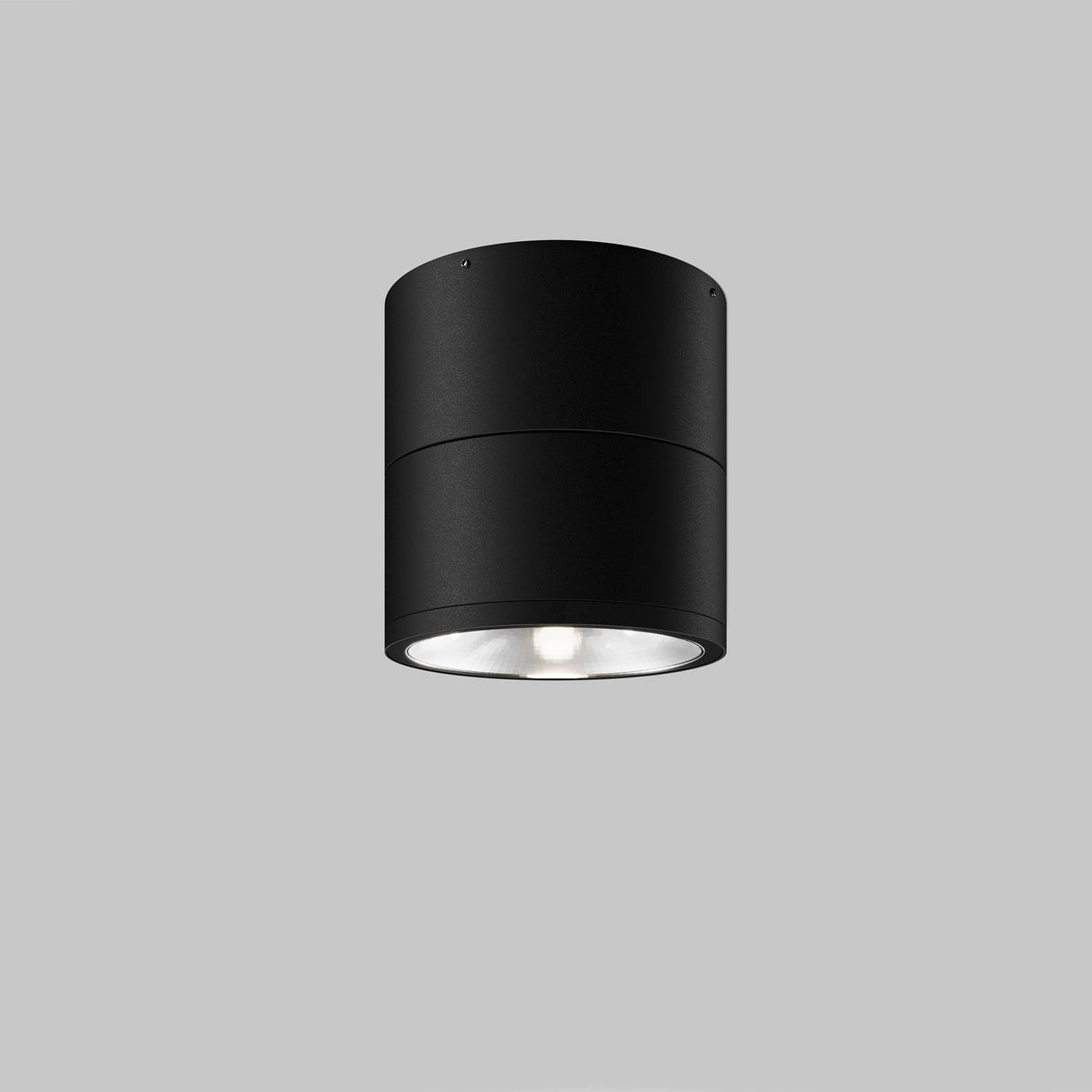 The Spin Outdoor LED Single Spotlight 12W 3000K in Graphite is a contemporary cylindrical ceiling fixture with a smooth finish and an IP54 rating, featuring a visible central lightbulb, offering durability and elegance against a plain gray background.
