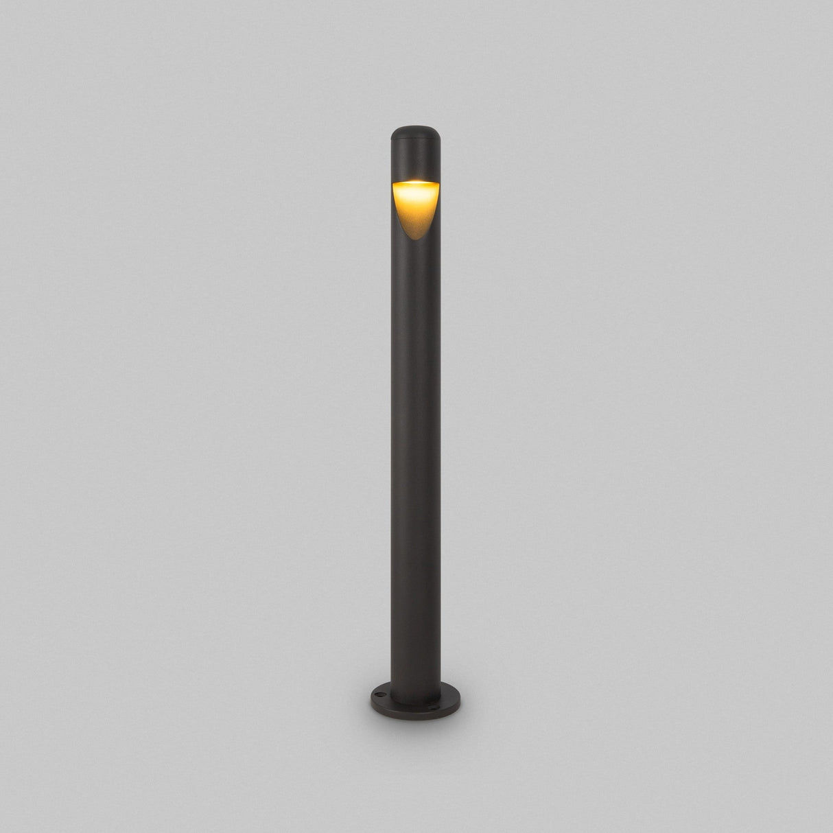 The Hagen LED Bollard Light 60cm in graphite is a minimalist outdoor lamp post with a warm glow near the top, set against a plain gray background. This sleek, cylindrical design embodies modern aesthetics and energy-efficient LED technology to enhance your outdoor space.