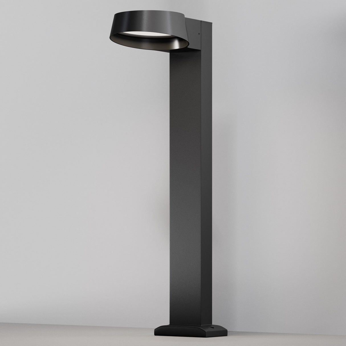 A Share LED Bollard Light in graphite, with its circular, angled shade and minimalist design, stands upright against a plain white background. Its sleek aesthetic features a sturdy rectangular base ideal for illuminating contemporary indoor and outdoor spaces.