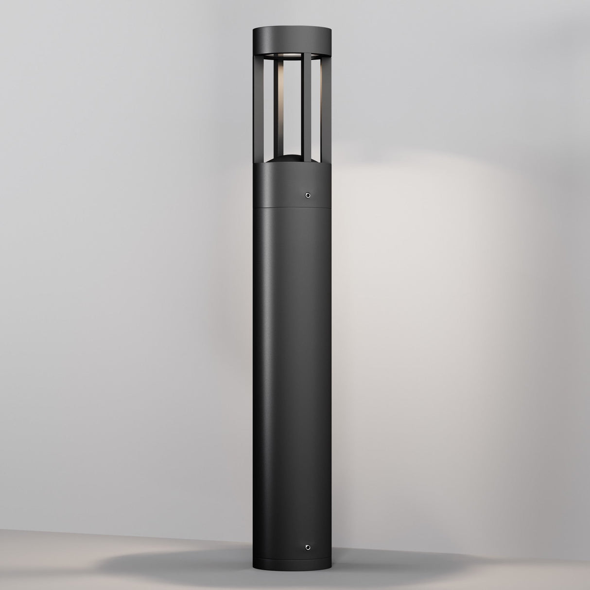 The Vint LED Bollard Light 3000K 9W - Graphite, 60cm features a sleek, modern design with a tall cylindrical shape and an open-topped metal lantern. Its graphite finish emits a soft glow against neutral surroundings, ideal for enhancing outdoor lighting ambiance.