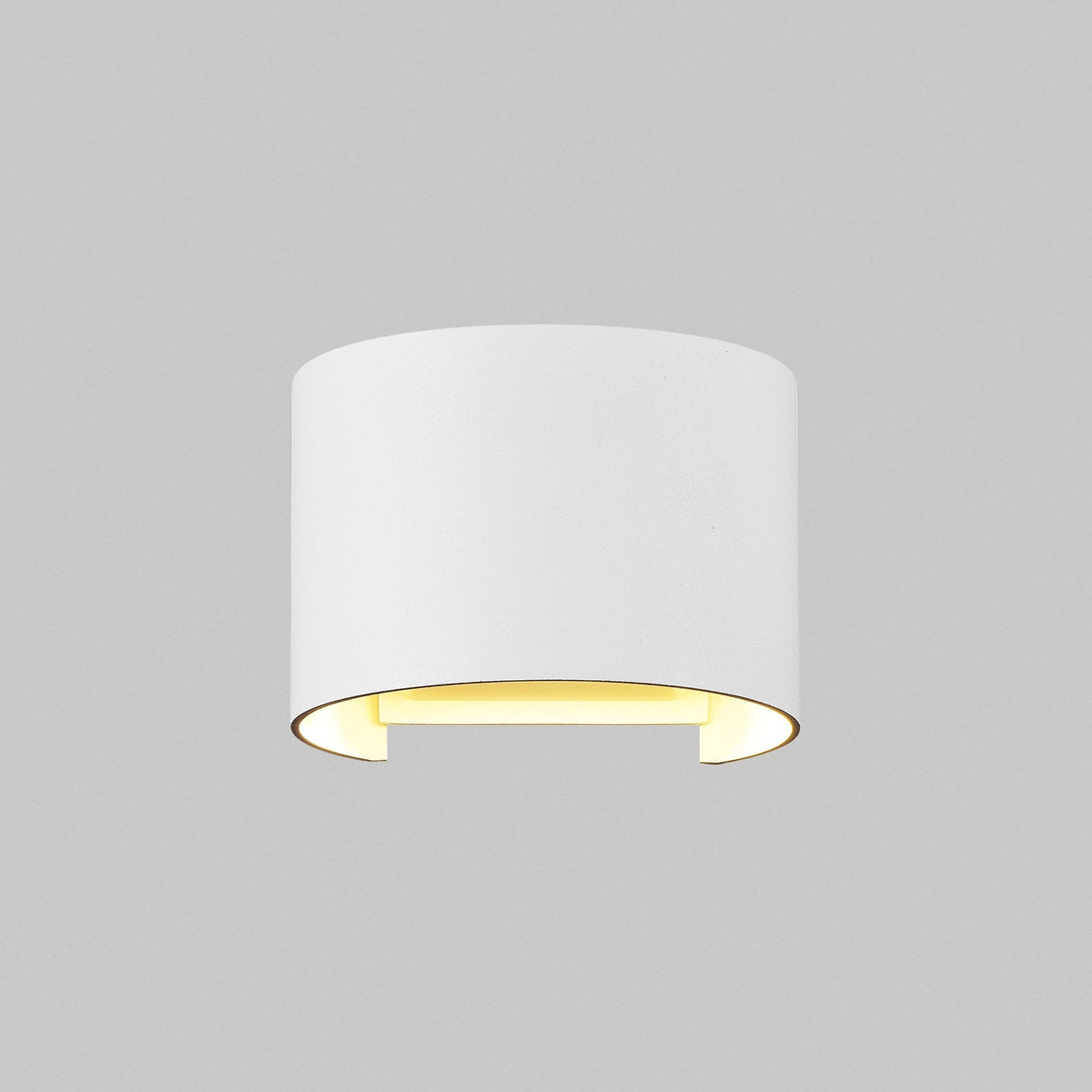 The Fulton Outdoor LED Oval Wall Light in white, made from corrosion-resistant aluminum, is wall-mounted and features a cylindrical design emitting a soft yellow glow from its open bottom against a plain gray background.
