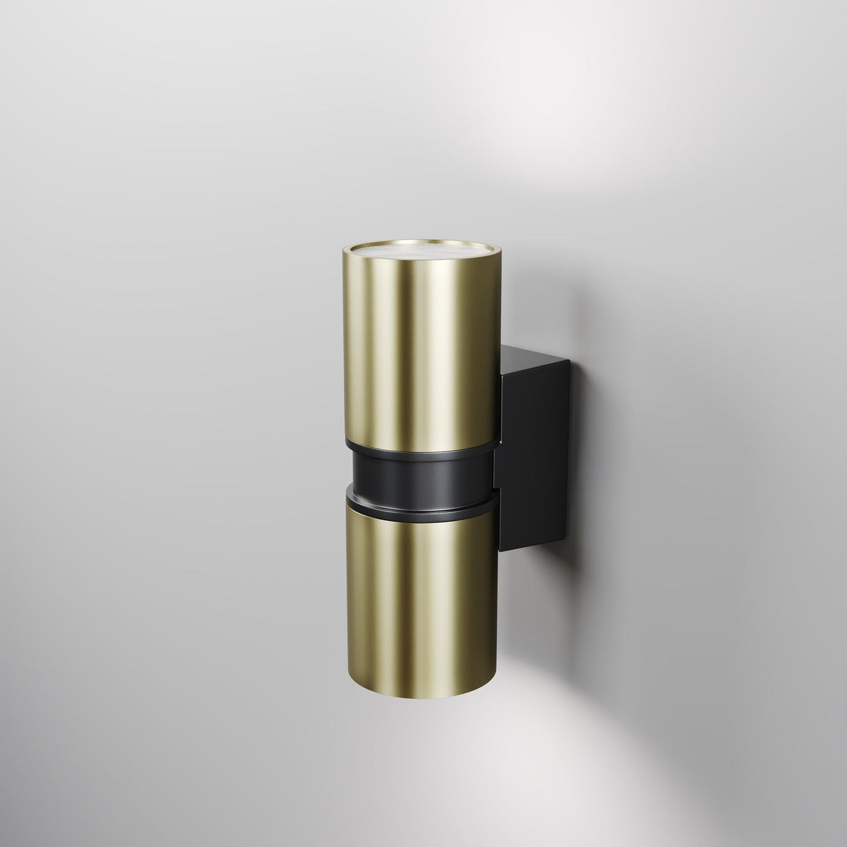The Bowery Outdoor 2 Light Wall Light - Brass features a modern, cylindrical design with a black bracket, mounted on a light gray wall. It offers dual light output for an ambient glow both upward and downward.