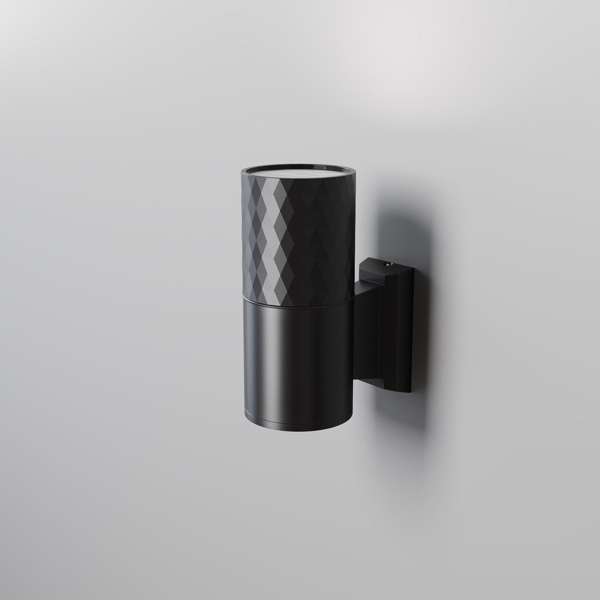 The Bowery Outdoor 1 Light Wall Light - Black (O583WL-01B) is a minimalist wall-mounted cylindrical sconce with a textured top and smooth bottom. Its modern design, coupled with an IP54 rating, effortlessly enhances any setting by casting subtle shadows on plain walls.