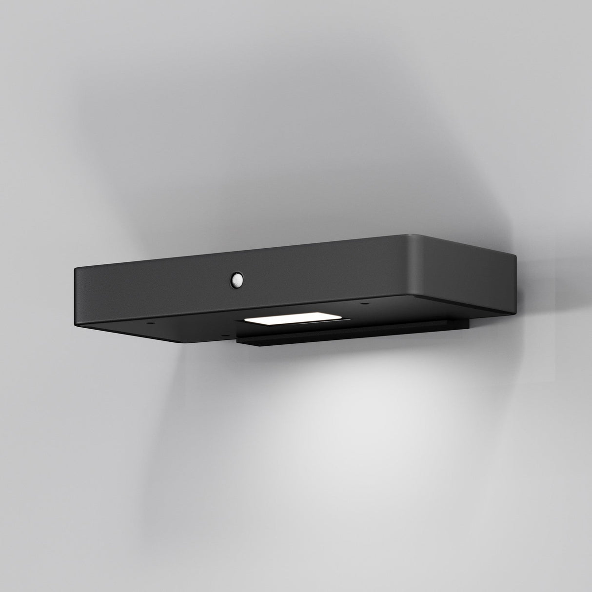 A Pir Outdoor LED Wall Light 3000K - Graphite is mounted on a light gray wall. The motion sensor directs the illumination downward, creating a gentle glow below.