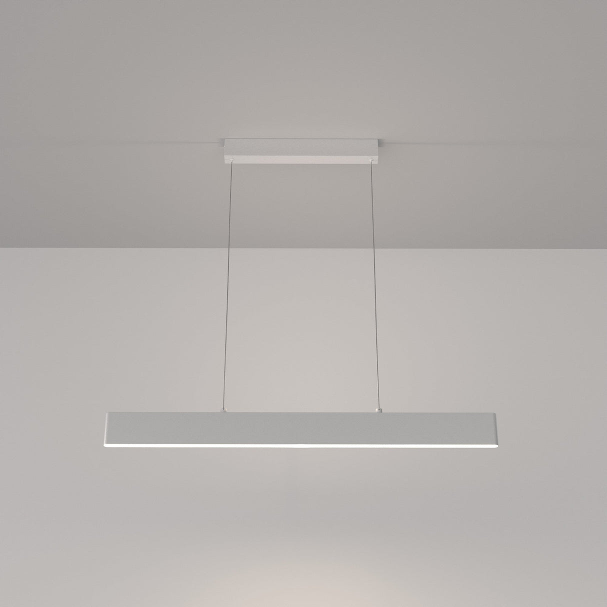 The Step LED Linear Suspension Light 4000K 23W - White showcases minimalist design with a sleek metal bar and energy-efficient lighting. Suspended by thin wires, it casts a warm glow in modern spaces, effortlessly blending style and functionality.