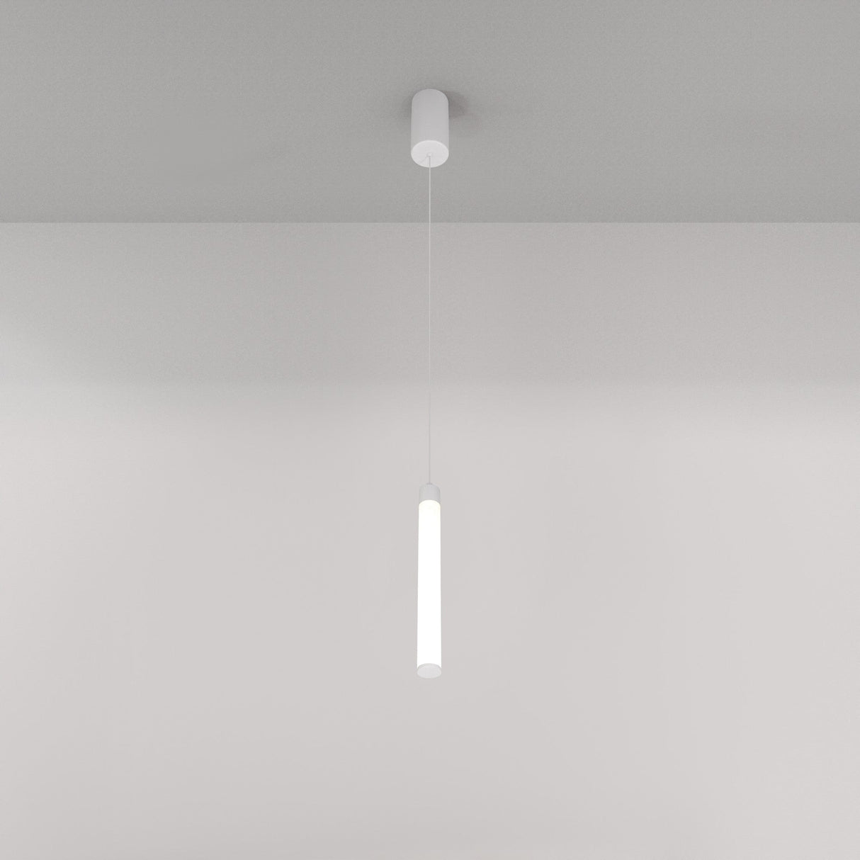 A minimalist white ceiling features the Ray LED Short Pendant Light in white, casting a soft glow. This modern interior creates a sleek ambiance against the plain background, epitomizing minimalist lighting design with its slender cylindrical form.