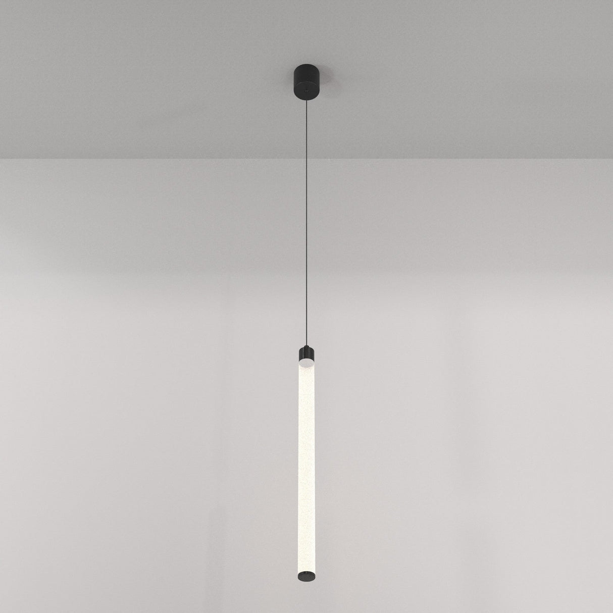 The Ray LED Long Pendant Light - Black & White is elegantly suspended by a thin wire, emitting an energy-efficient soft glow. It features black end caps and contrasts against a plain light-colored wall.