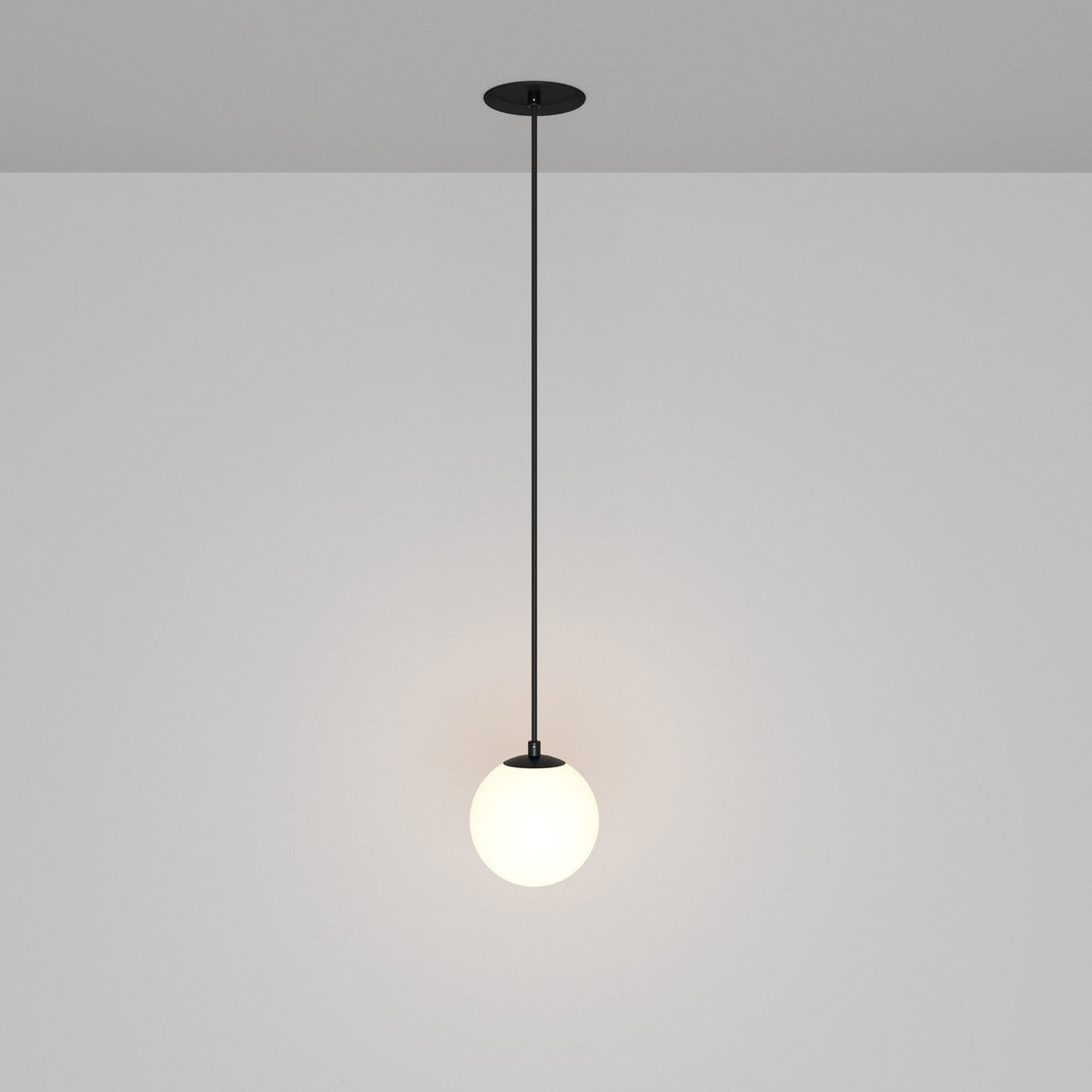 The Luna LED Recessed Globe Pendant Light 10cm 3000K in black and white showcases a minimalist black cord design with a spherical white lampshade, providing a soft glow and energy efficiency against a neutral gray background.