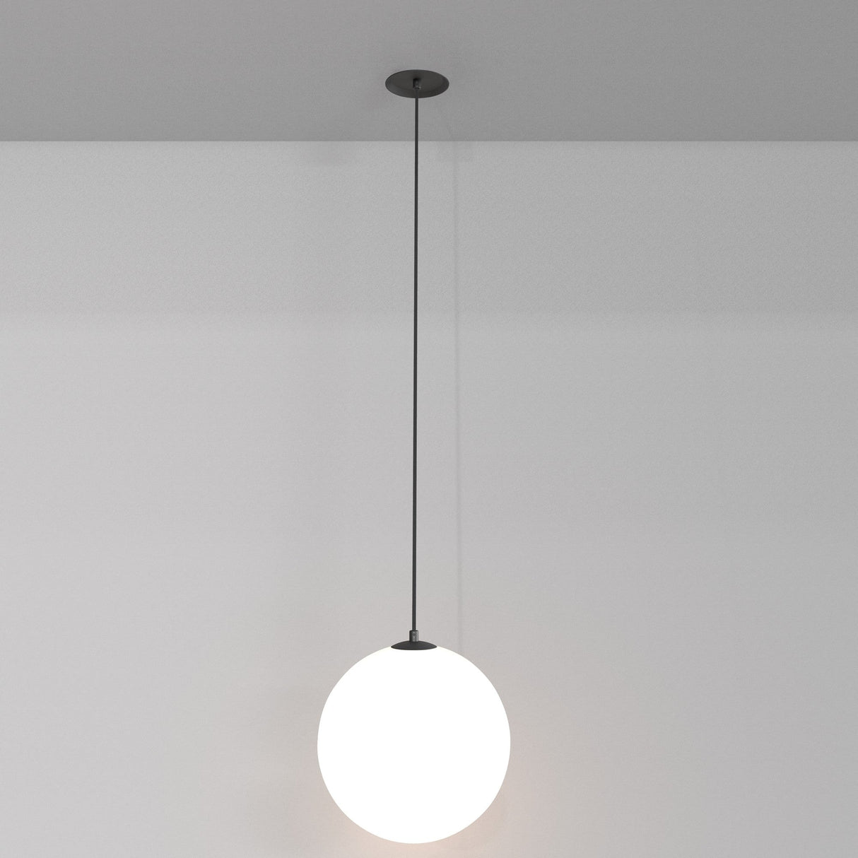 The Luna LED Recessed Globe Pendant Light 20cm 3000K features a sleek, minimalist sphere with a frosted white finish hanging from a thin black rod, using energy-efficient LEDs to emit a subtle glow casting soft shadows on neutral walls.