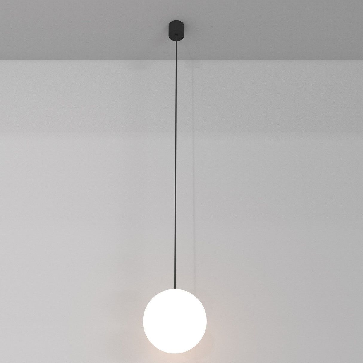 The Luna LED Globe Pendant Light 20cm 4000K in black and white illuminates a plain, light-colored wall with its sleek design, ideal for modern interiors seeking energy-efficient lighting solutions.