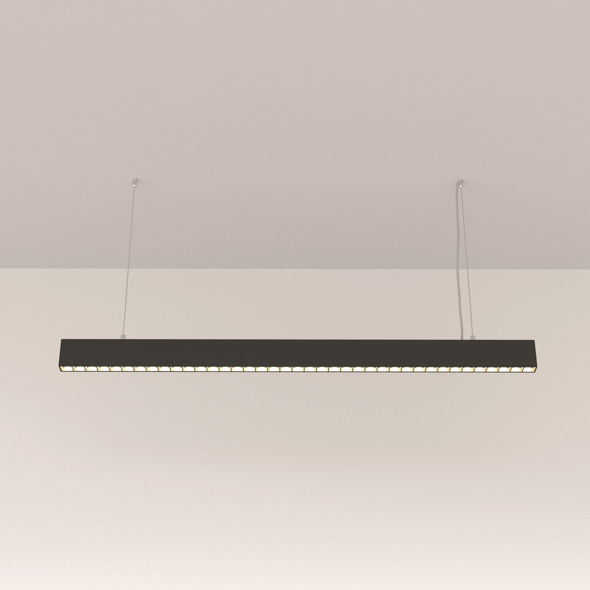 The Points LED Linear Suspension Light - Black is suspended elegantly by two thin wires from the ceiling, boasting an adjustable height for versatility while casting a gentle glow beneath it against a simple white background.