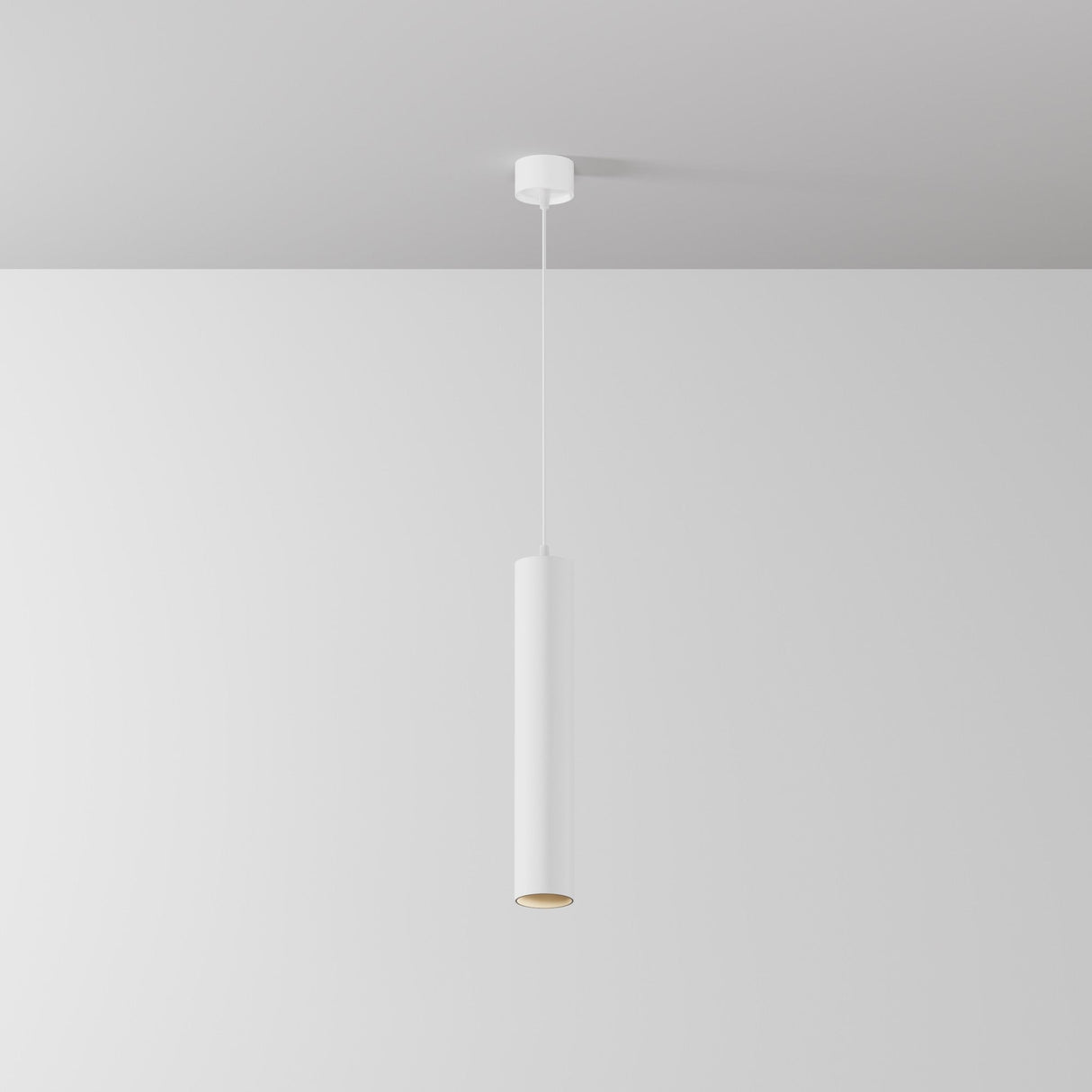The Focus LED Pendant Light 3000K - White showcases a minimalist cylindrical design with a sleek white finish, elegantly suspended from a white ceiling against a light-colored wall.