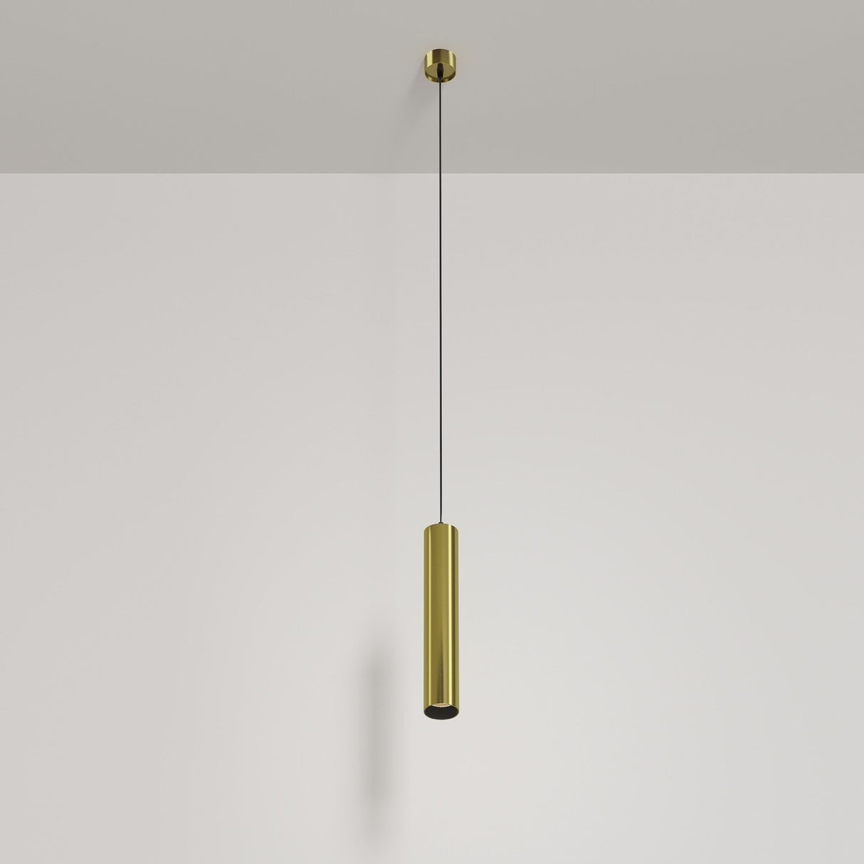 The Focus LED Pendant Light 3000K - Brass showcases minimalist elegance with a sleek cylindrical brass shade, suspended by a thin black wire against a white backdrop.