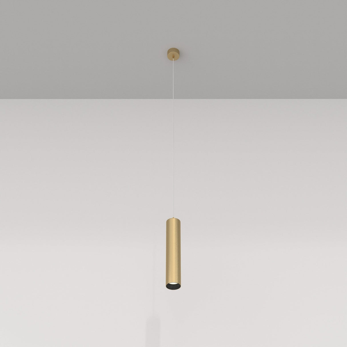 The Focus Single Pendant Light in matte gold, with its minimalist design, hangs elegantly from the ceiling against a pristine white wall.