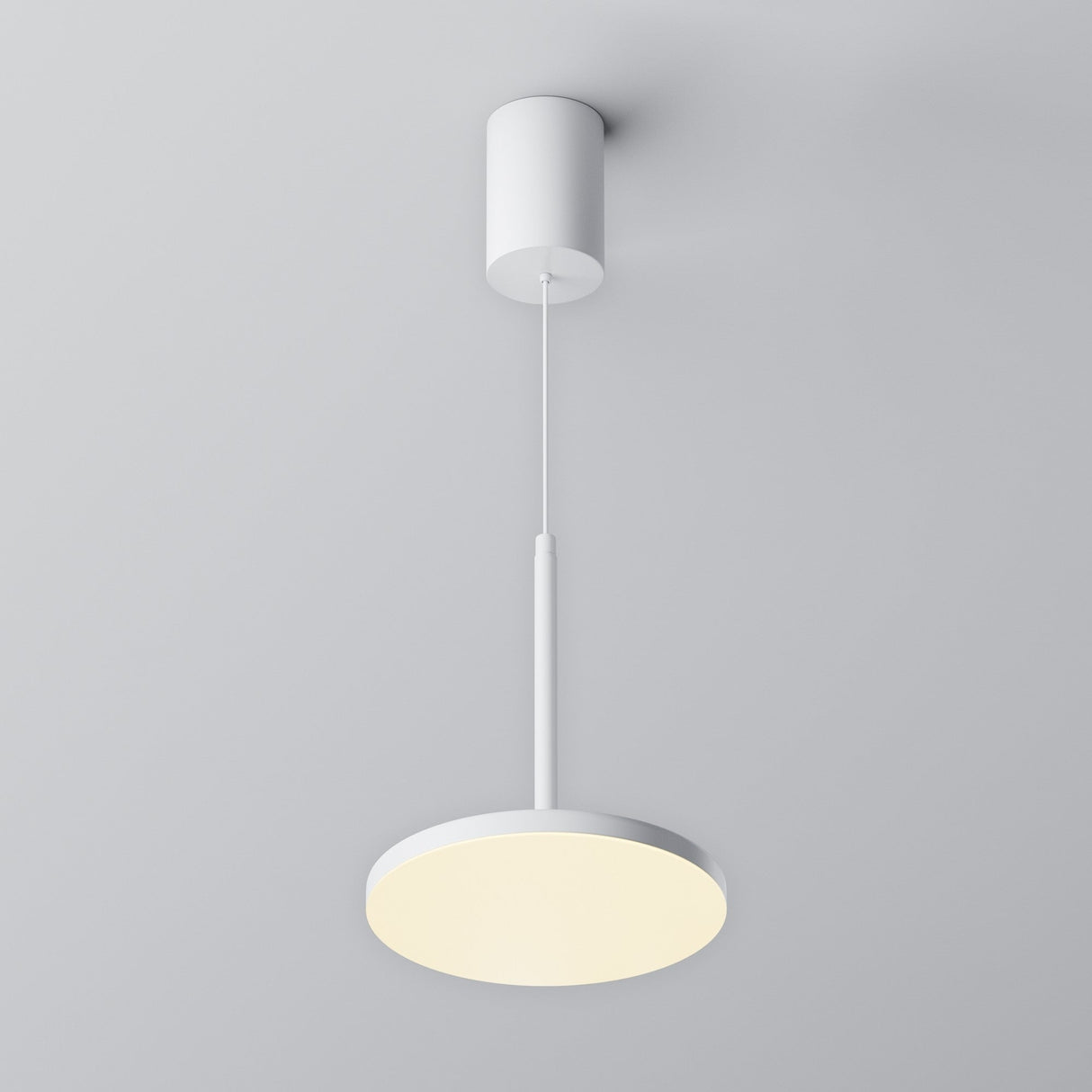 The Plato LED Pendant Light - White features a modern, minimalist design with a round, white shade suspended by a thin cord. It includes a cylindrical ceiling mount and energy-efficient LED technology, emitting a soft, warm glow against a light gray background.