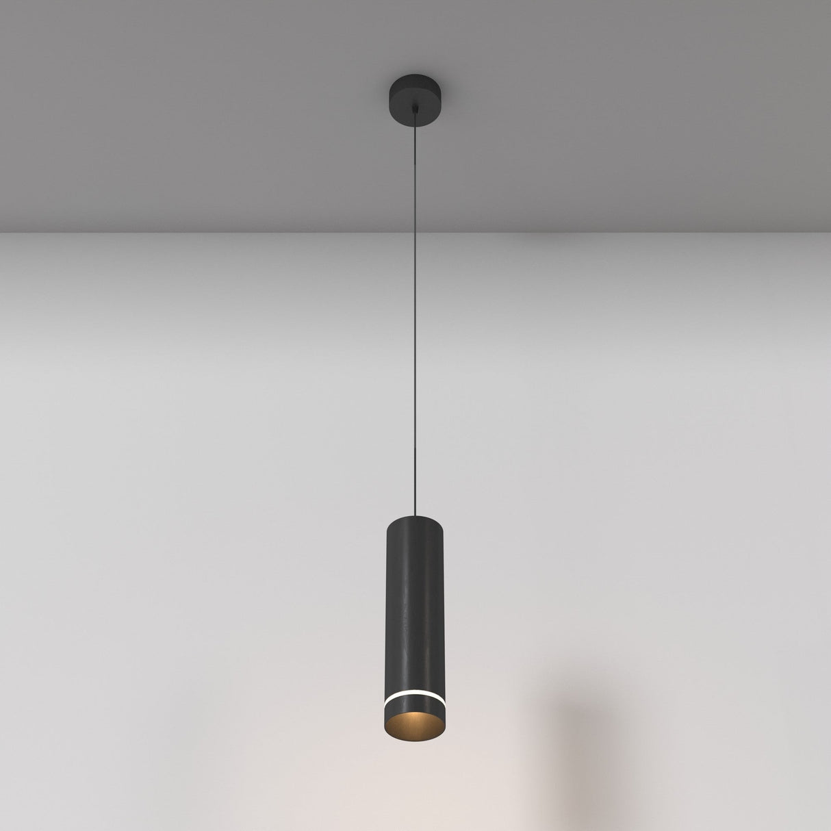 The Orlo LED Pendant Light 3000K in black, featuring a sleek cylindrical design and adjustable suspension, hangs stylishly from the ceiling, casting a subtle glow on the neutral wall while highlighting minimalist simplicity and elegance.