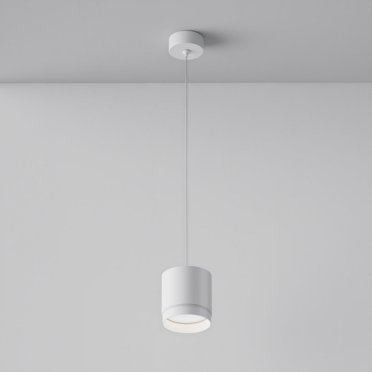 The Polar Short Round Pendant Light - White elegantly hangs from the ceiling, casting a warm glow that enhances modern interiors and gently illuminates the smooth, plain wall around it.