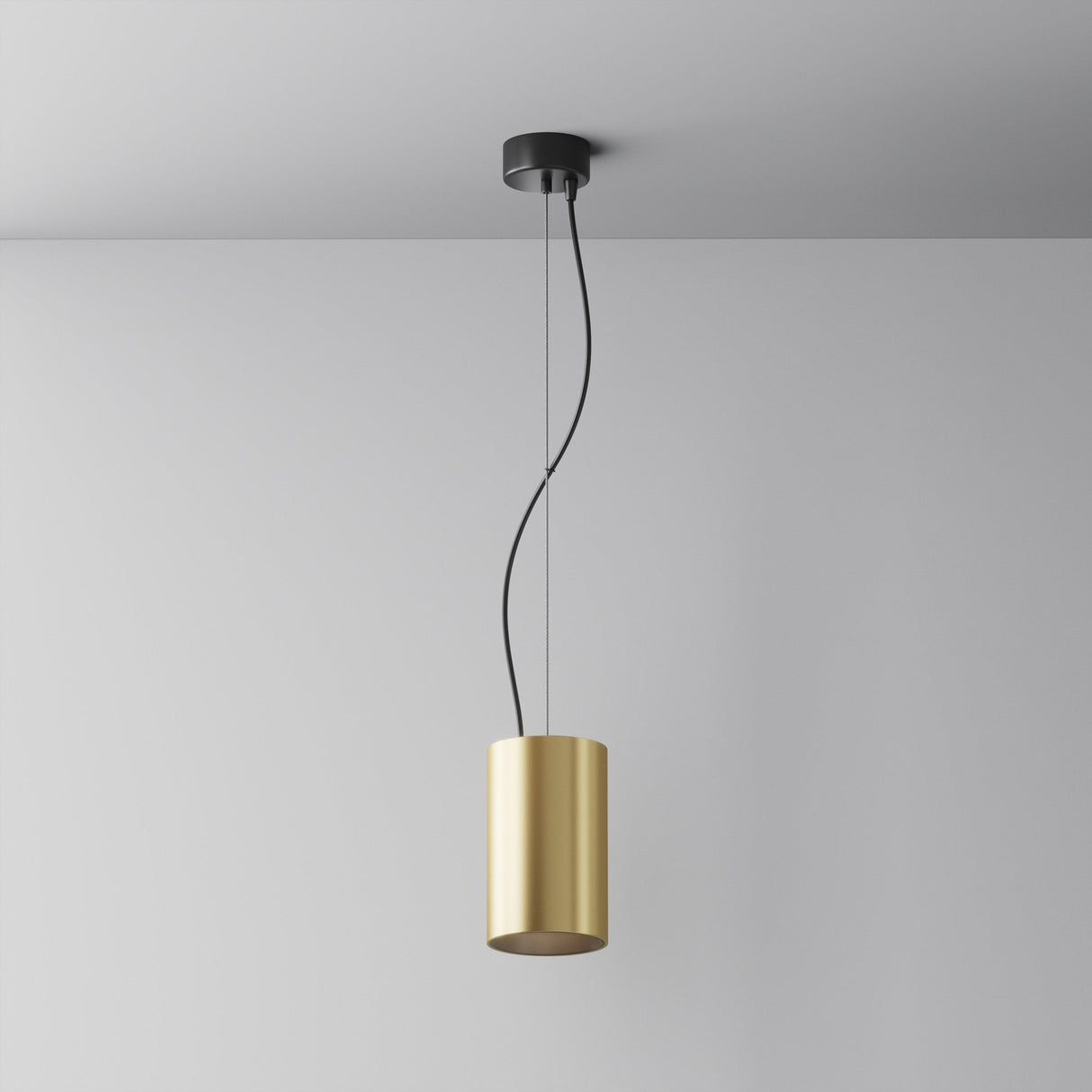 The Efir LED Pendant Light 25W - Matte Gold has a sleek, matte gold cylindrical shade hanging elegantly from a black mount. Suspended by two black wires, it forms gentle curves against a white ceiling and wall, casting warm white light throughout the room.