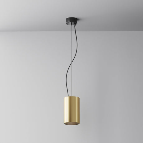 The Efir LED Pendant Light 25W - Matte Gold has a sleek, matte gold cylindrical shade hanging elegantly from a black mount. Suspended by two black wires, it forms gentle curves against a white ceiling and wall, casting warm white light throughout the room.