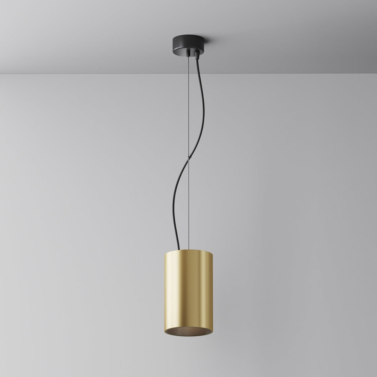 The Efir LED Pendant Light 33W - Matte Gold features a cylinder shade, suspended by a black cord and mount. This energy-efficient fixture complements a plain white wall with a gray ceiling, merging modern style with sustainability.