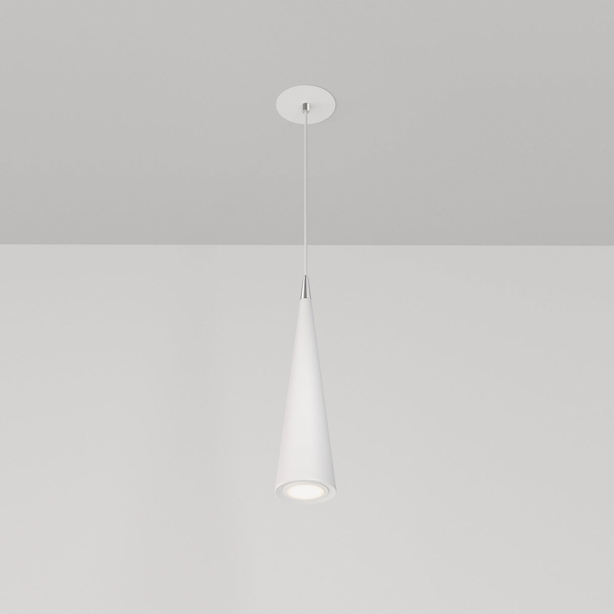 The Nevill Conical Pendant Light - White, with its minimalist cone-shaped shade, hangs elegantly from the ceiling, casting a gentle downward glow against a white backdrop when illuminated.
