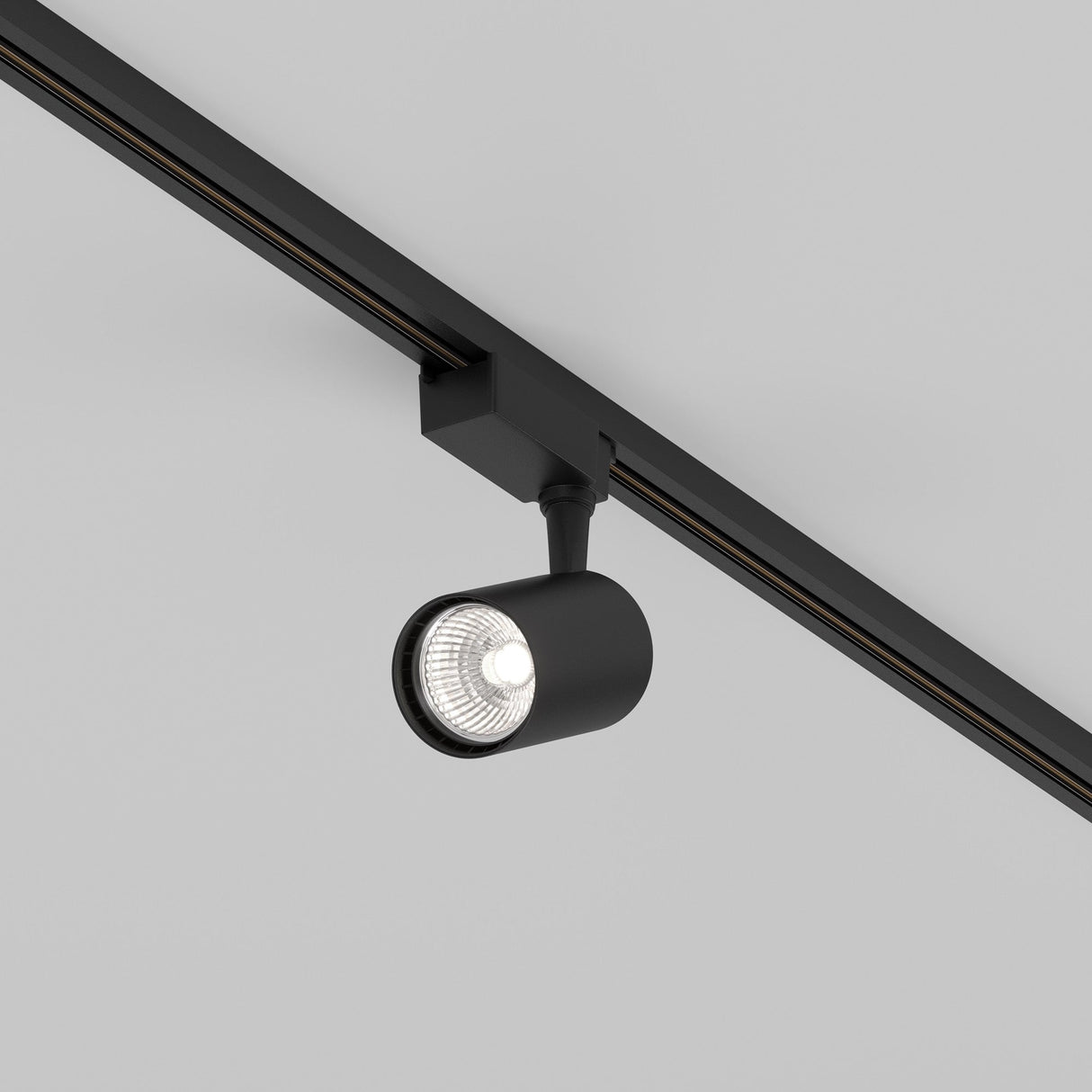 The Vuoro S LED Single Phase Unity Track Spotlight, a sleek black 10W cylindrical fixture mounted on a ceiling track, features modern energy-efficient 4000K lighting that brightly illuminates the space below.