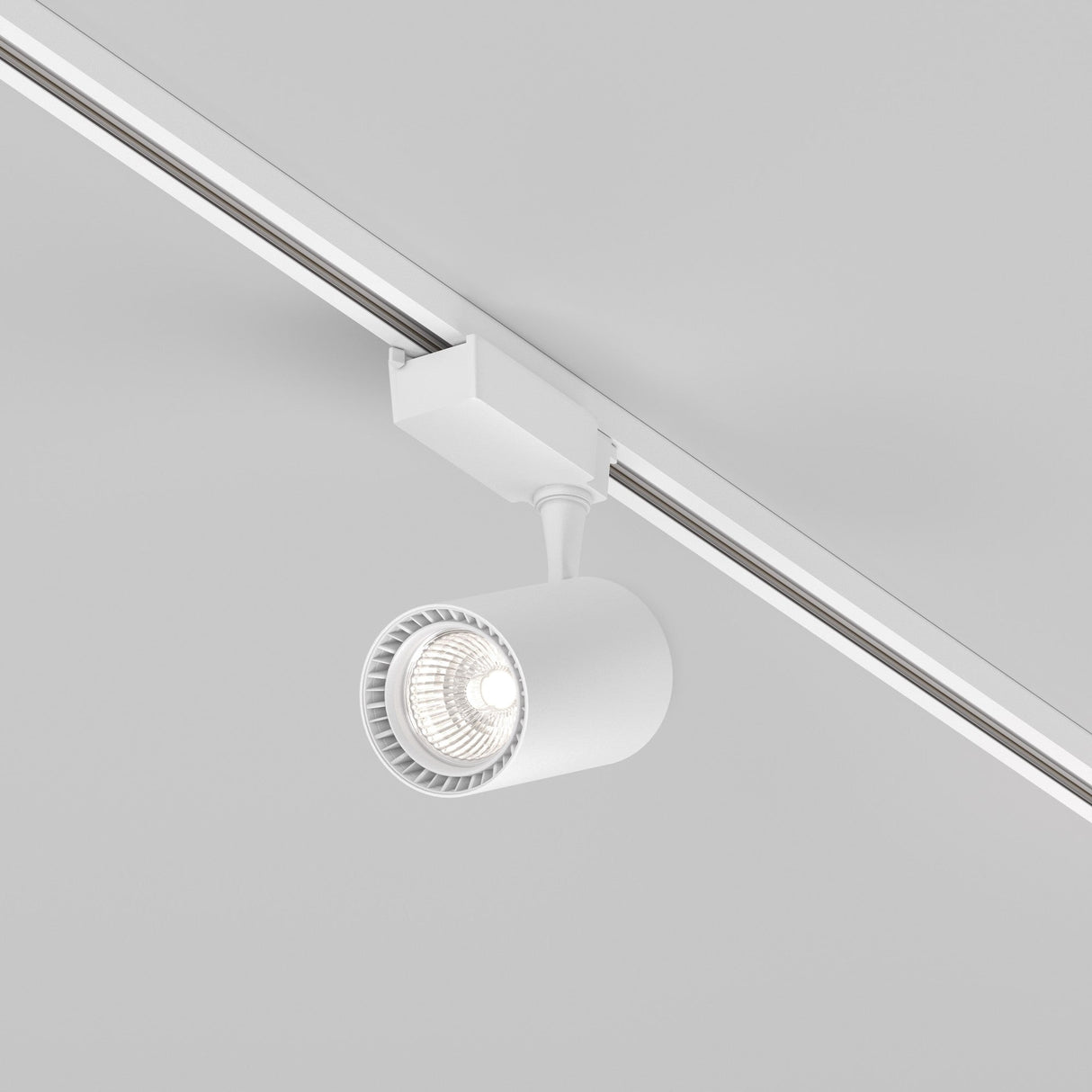 The Vuoro S LED Single Phase Unity Track Spotlight offers a sleek 15W cylindrical design in white, spotlighting against the plain ceiling with a bright 4000K beam. Its adjustable light direction enables precise focusing when mounted on its straight metal track.