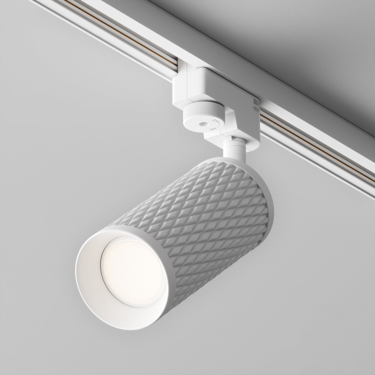 Close-up of the Focus Design Single Phase Unity Track Spotlight in white with a cylindrical, textured casing. It features an adjustable GU10 base spotlight and is mounted on a white track, contrasting against the gray ceiling to provide modern, minimalist directional lighting.