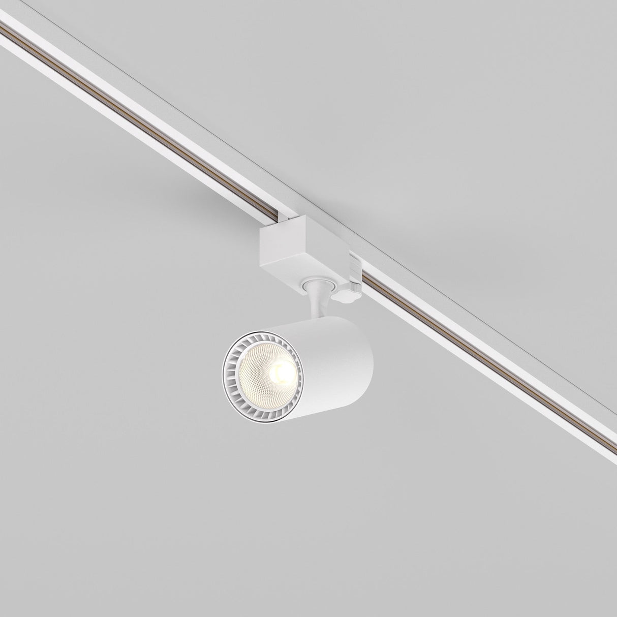 The Vuoro S 3-Circuit Trinity Track LED Spotlight 10W 3000K in white is mounted on a ceiling rail, providing focused downward lighting with its modern cylindrical design against a neutral background.