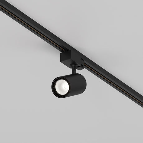 The Vuoro S 3-Circuit Trinity Track LED Spotlight, 10W 4000K in black, features a cylindrical design with an adjustable swivel head and is mounted on a 3-circuit track rail, casting downward light against a white ceiling.