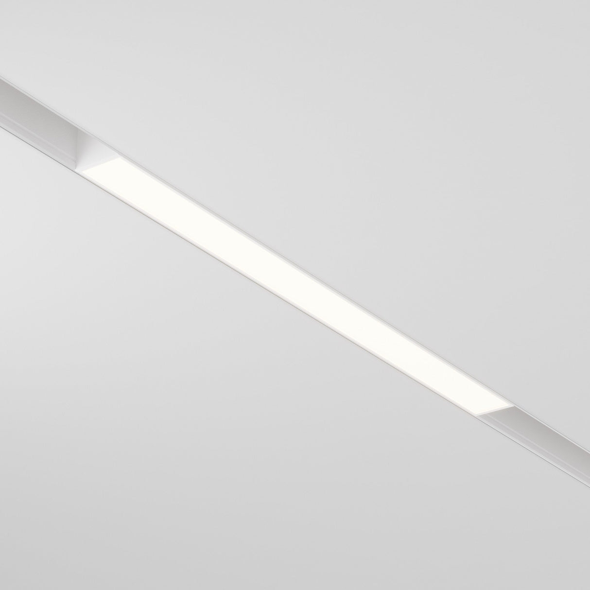 The Basis LED Linear Track Light for Magnetic Exility 12W 3000K - White is a ceiling-mounted fixture featuring sleek design and Warm Glow Lighting, casting an even white glow against a plain white ceiling.