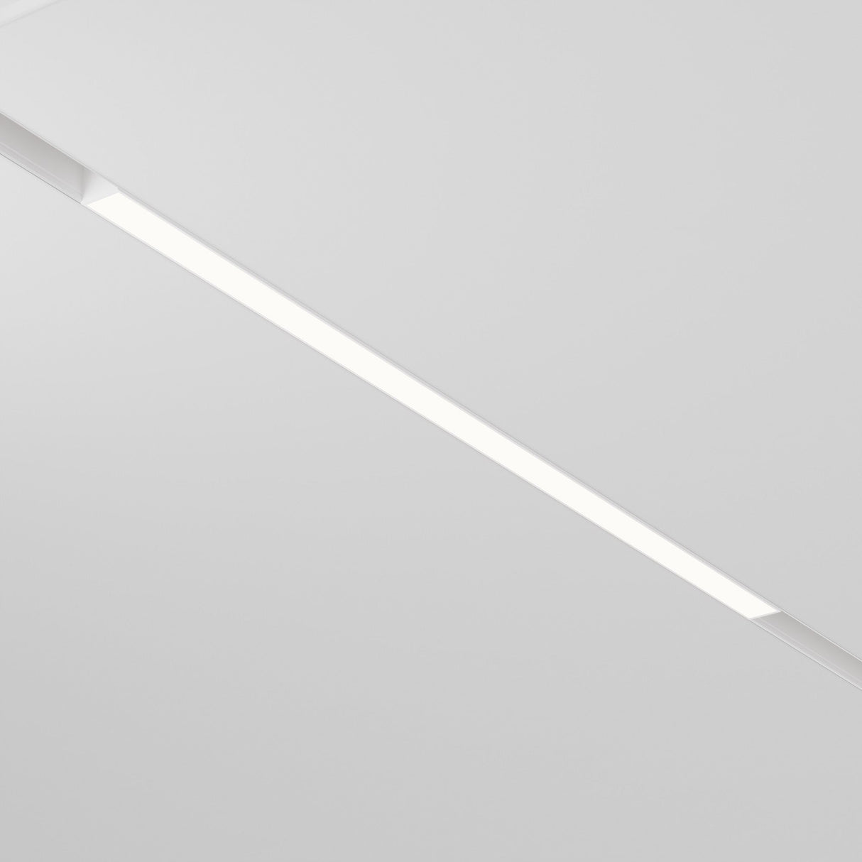 The Basis LED Linear Track Light for Magnetic Exility 24W 4000K - White features a minimalistic recessed design. Its sleek, narrow strip against the smooth white ceiling casts a cool white light, offering an understated and efficient modern style.