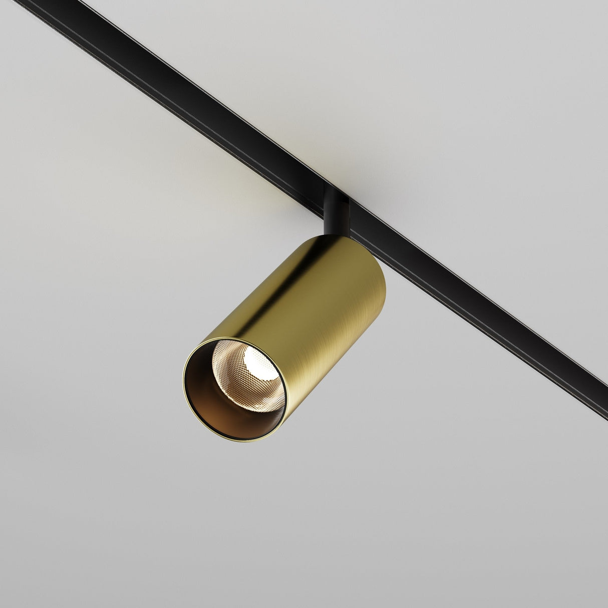 A sleek black and brass Focus LED Magnetic Exility Track Spotlight (12W, 3000K) is mounted on a black rail against a white ceiling. Its turned on, casting a focused beam with high color rendering index directly downward.