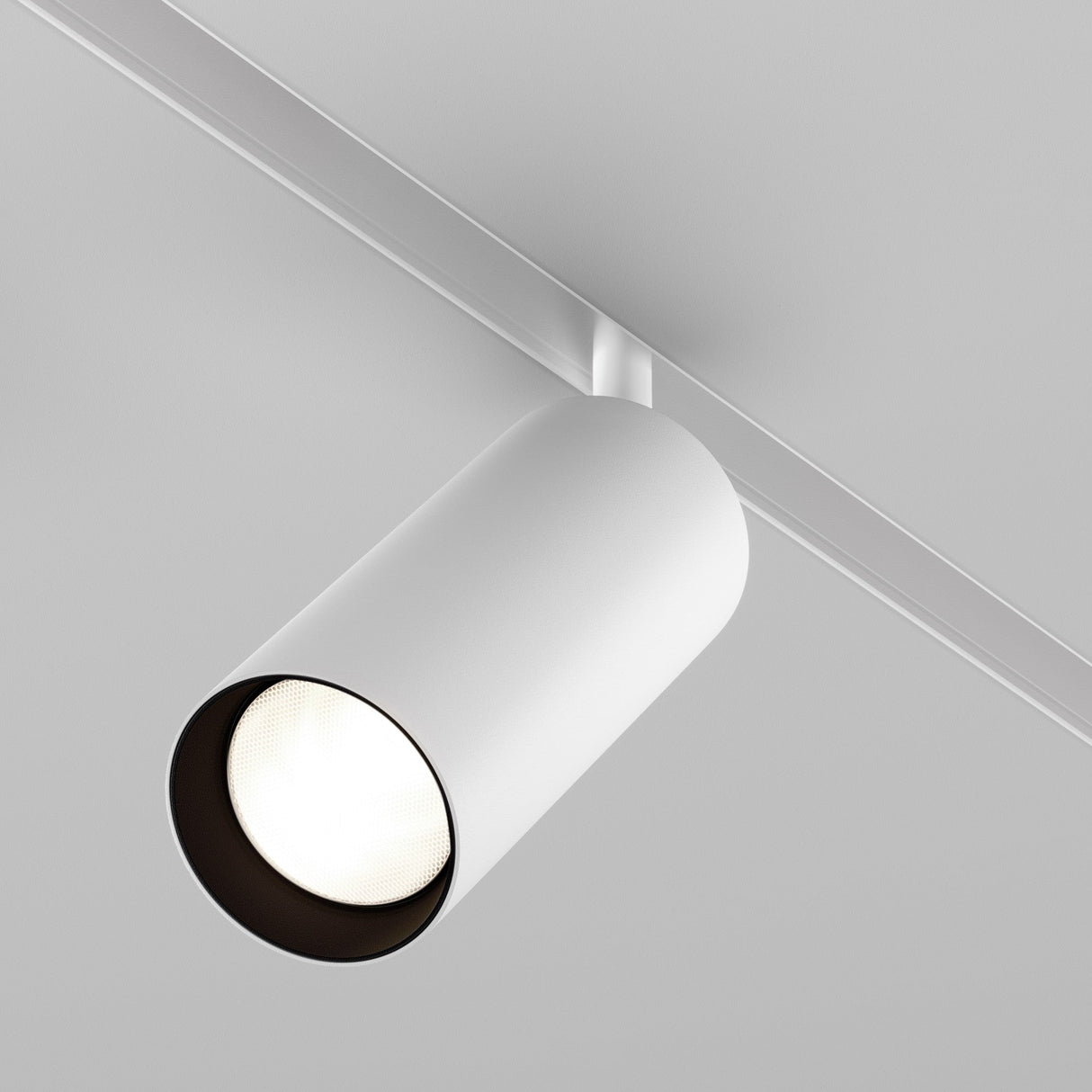 A close-up of the Focus LED Magnetic Exility Track Spotlight 20W 4000K - White mounted on a ceiling. The sleek, cylindrical fixture is minimalist and energy-efficient, turned on to cast a subtle glow with its high color rendering index.
