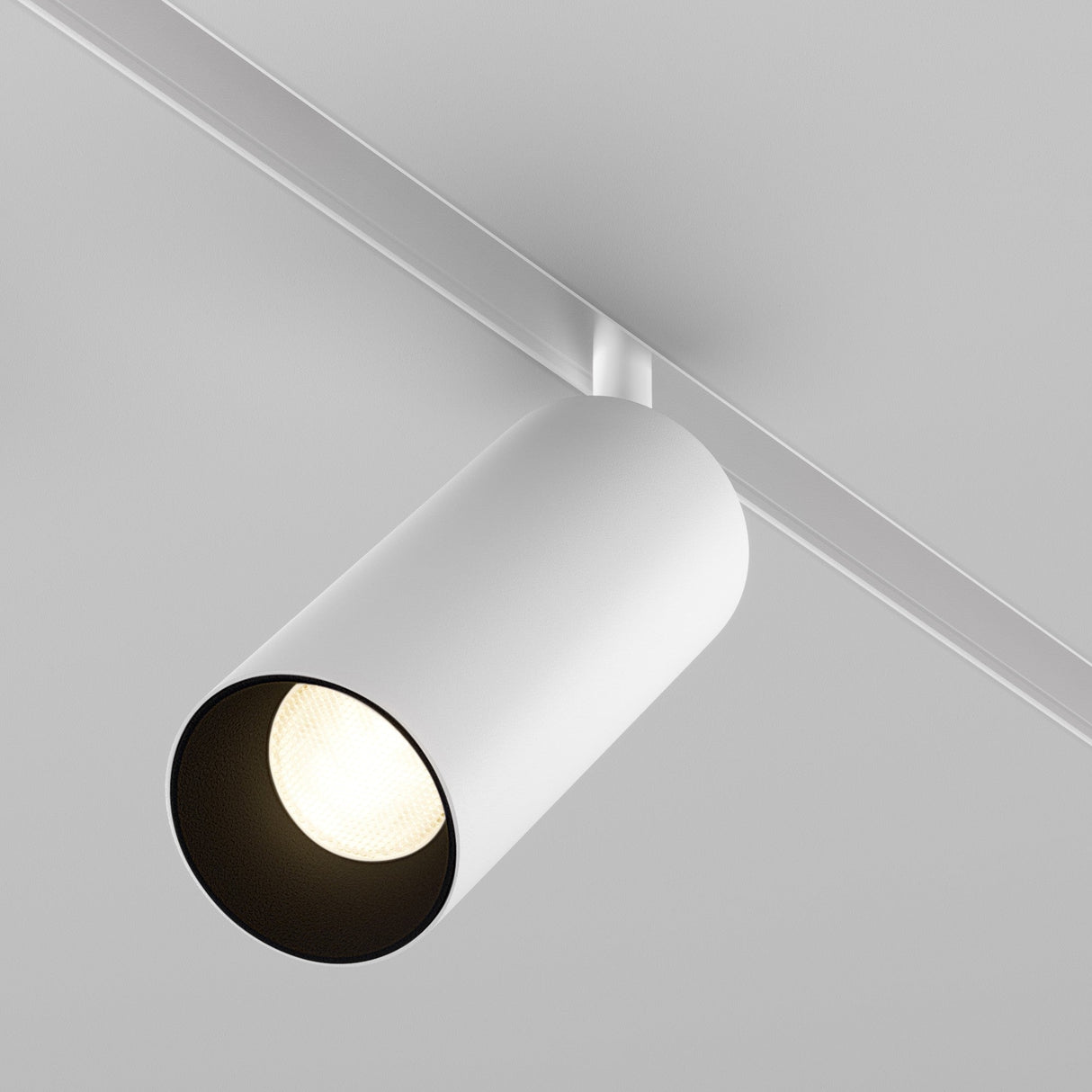 The Focus LED CCT Magnetic Exility Track Spotlight 20W (2700-6000K) in white is a modern, cylindrical fixture on a ceiling rail, angled downward to illuminate below. Its dimmable feature adds versatility against the light gray ceiling.